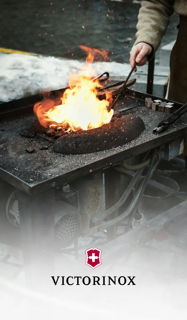 Victorinox: Handwerkskunst und Tradition Ein Schmied bei der Arbeit mit glühendem Eisen und Funkenflug, eine atmosphärische Darstellung der handwerklichen Qualität hinter einem Victorinox Luxus Werbeartikel.
